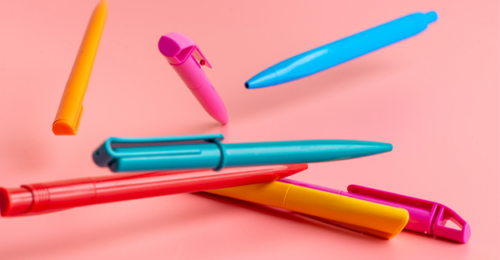 Multicolored pens on a pink background