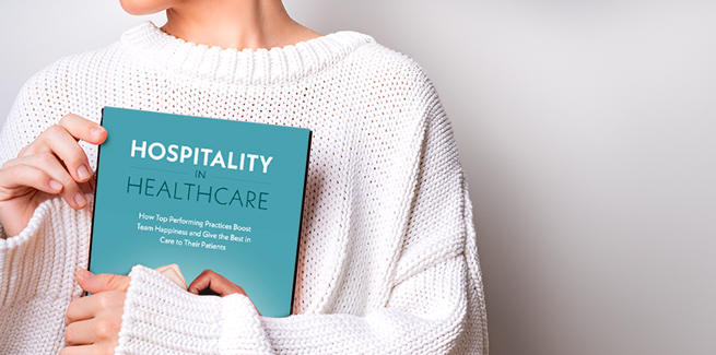 A woman holds the book Hospitality in Healthcare by Debbie Boone, CVPM