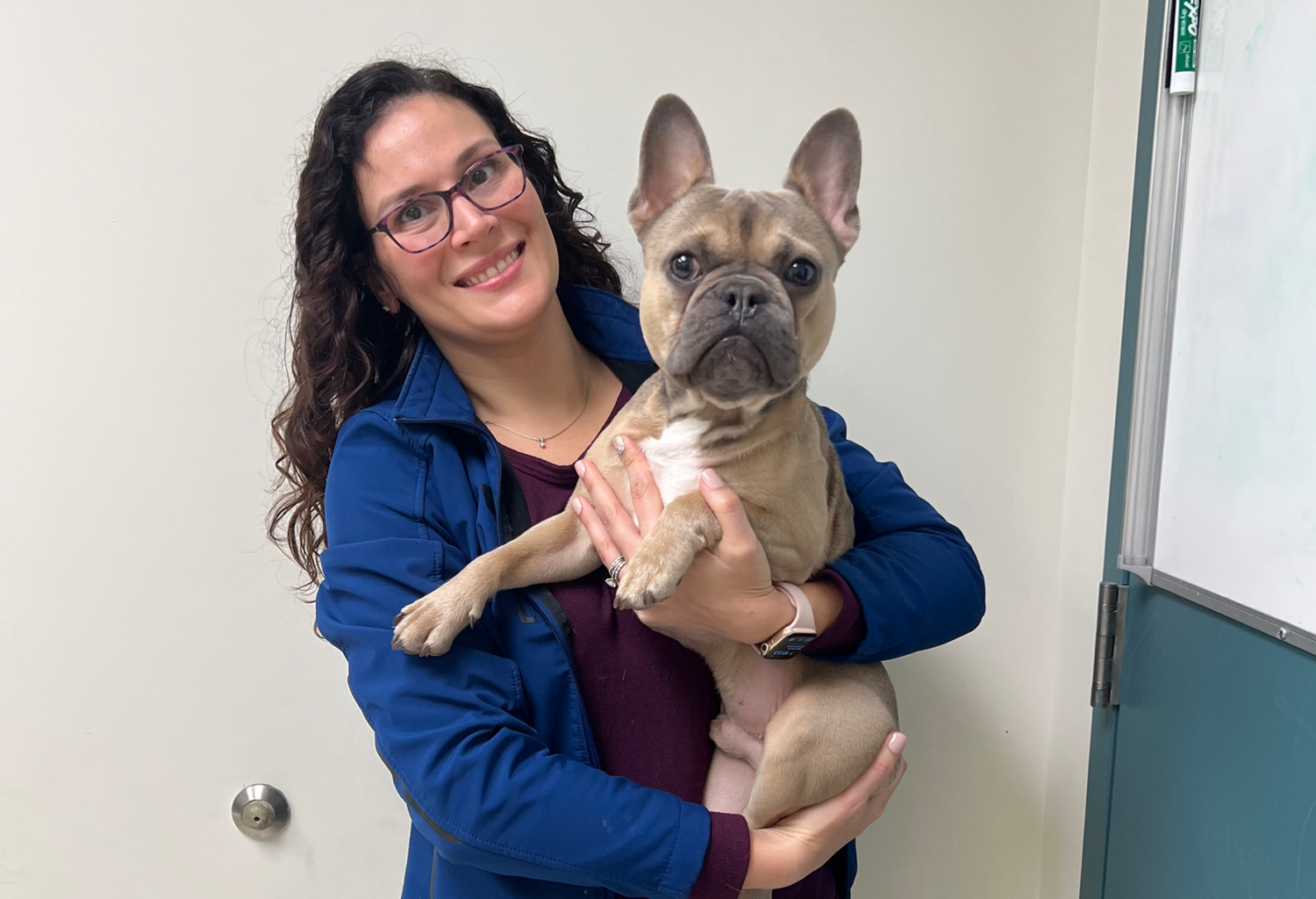 worker holding dog at breathe clinic and smiling