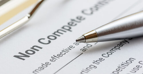 Closeup photo of non-compete clause paperwork on a clipboard with a pen on top of it