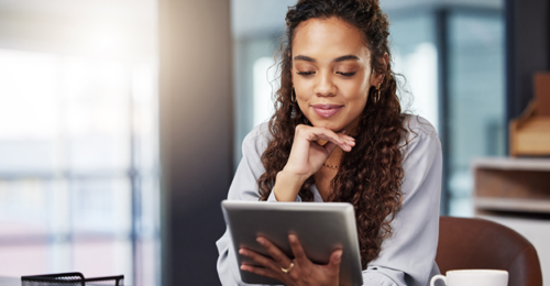 Image of a woman looking at a tablet for a job. Hiring and retaining employees is important.