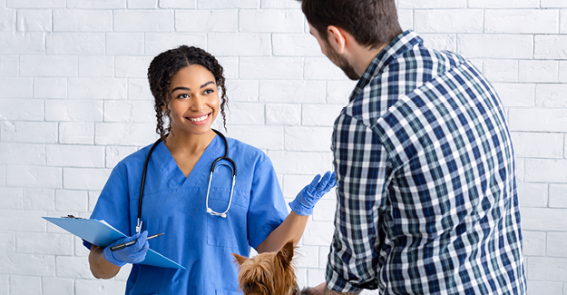 A veterinary technician talking to a client about his dog.