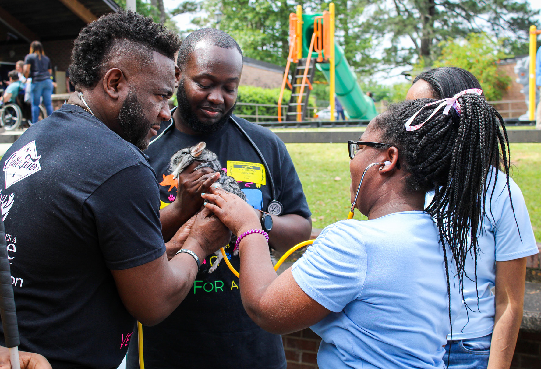 Vernard Hodges, DVM, (far left) helps to hold a chinchilla while a student listens to its heart.