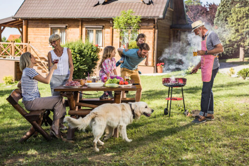 Family with dog grilling and sitting around picnic table