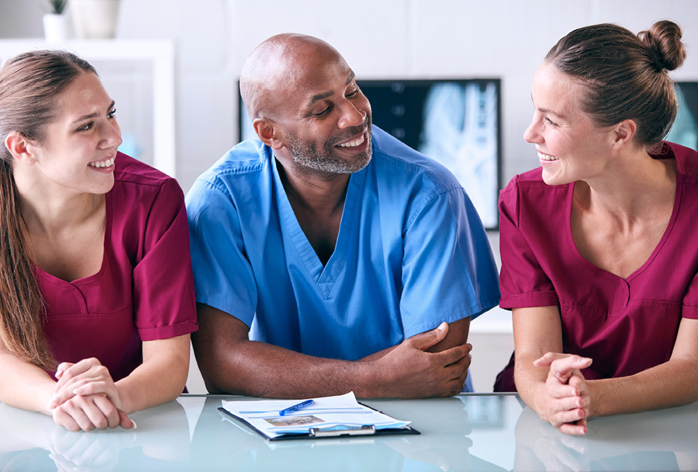 3 people in scrubs talking